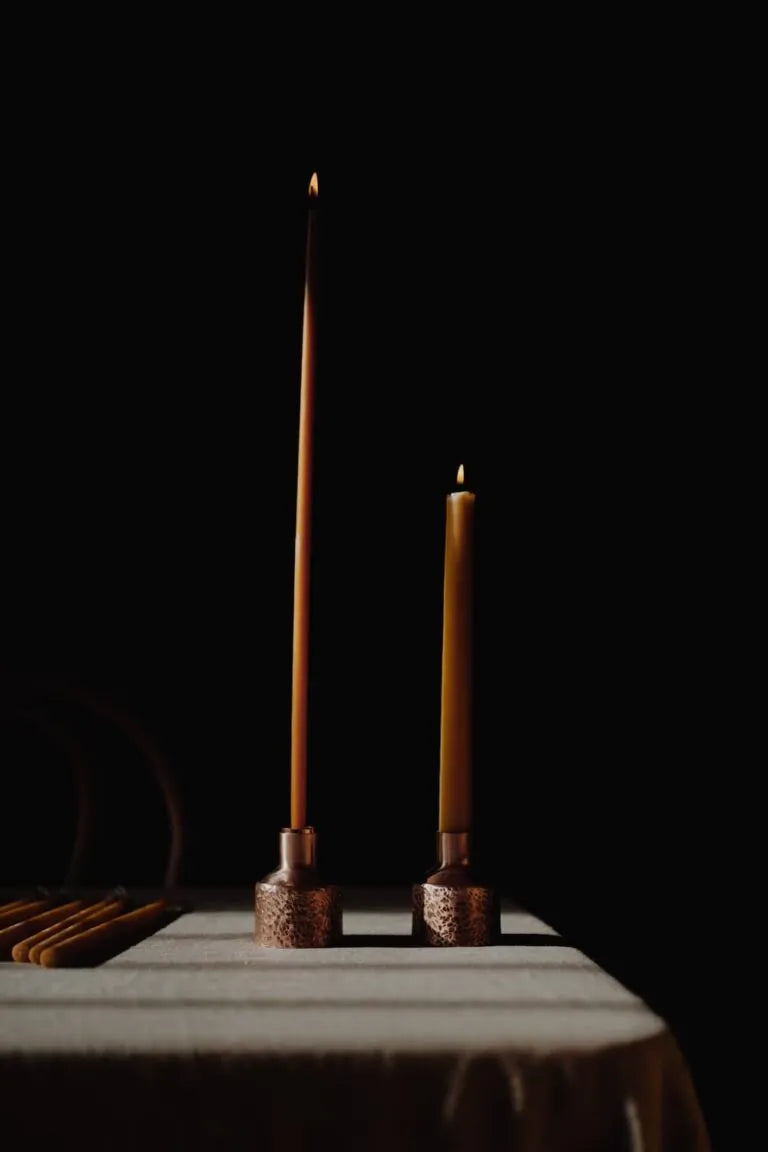 beeswax candles in copper holders on a table